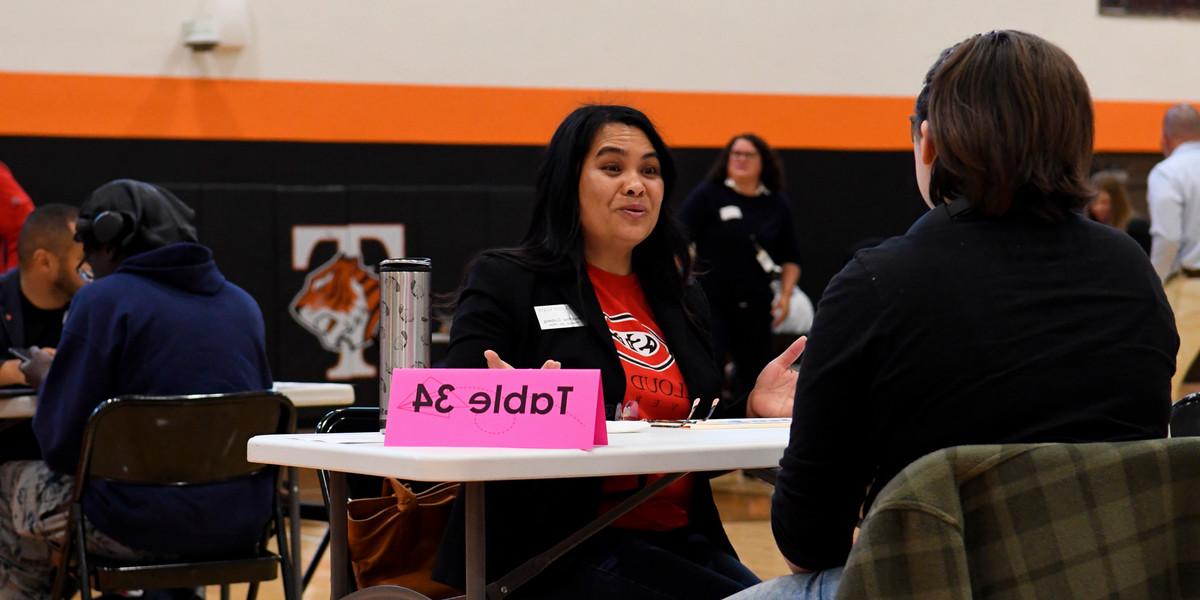 An SCSU volunteer speaks with a student in the Tech High School Gymnasium