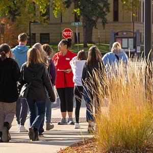 An SCSU tour guide walks a group of prospective studetns and family members across campus